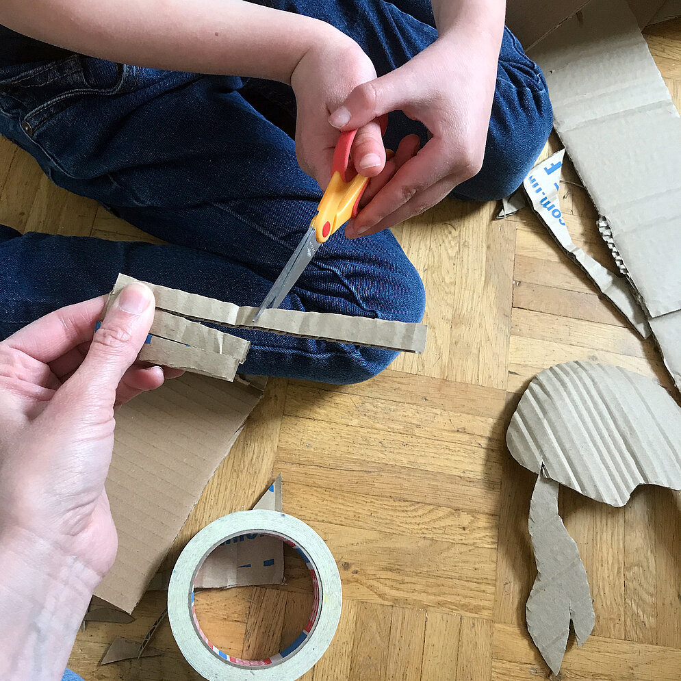 Kinder schneiden ein Stück Pappe